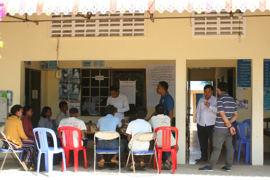 Volunteer malaria workers meet in the shade of a health center.