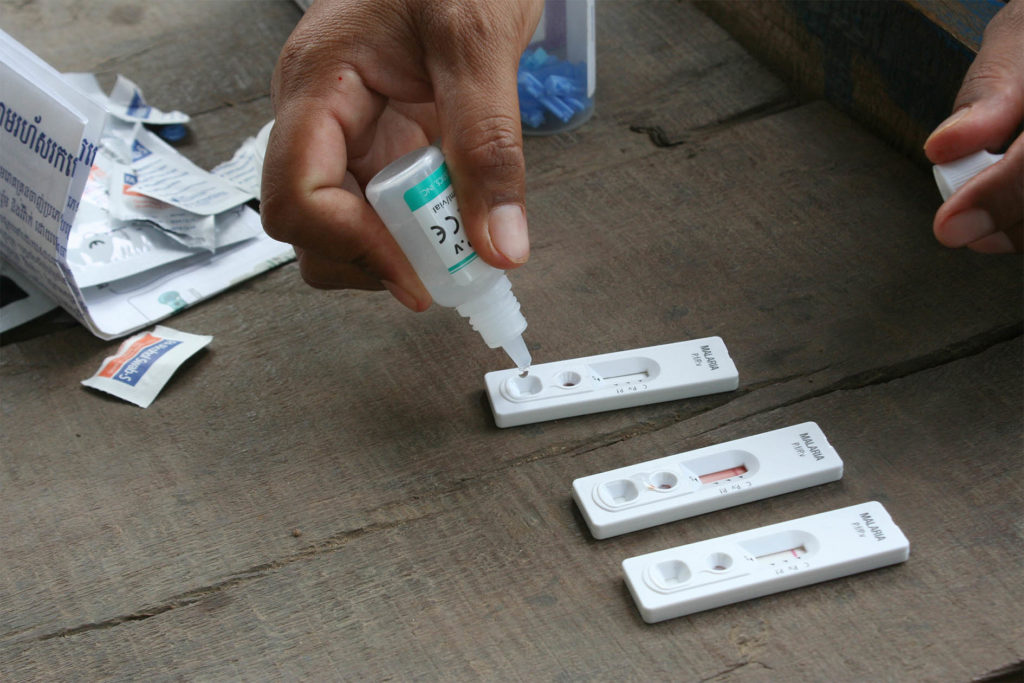 A close up image of Savry, a volunteer malaria worker, preparing test strips.