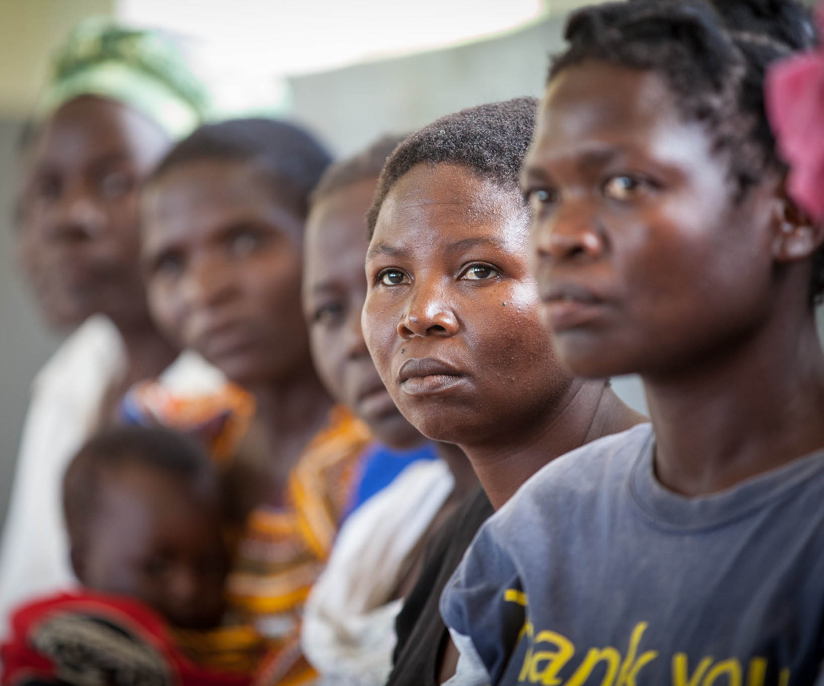 A woman sits in a row with other women, waiting for her turn at a health center in Malawi.