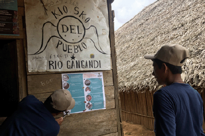 A man pins a poster the wall of a building while another looks on.