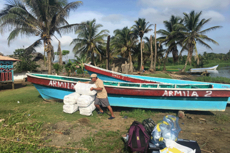 A malaria worker piles mosquito nets beside a boat.