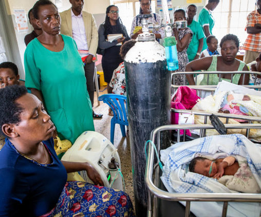 A mother sits beside her infant's hospital bed while oxygen is administered to the child.