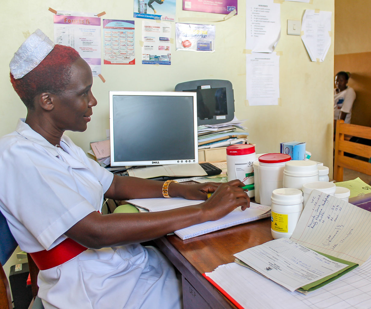 A nurse sits at her desk, consulting with a patient.