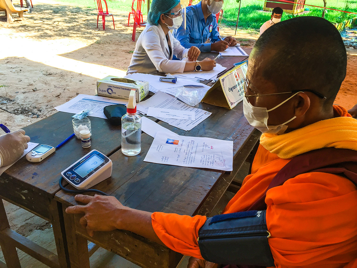 A religious community member receives a blood pressure test during a visit for COVID-19 vaccination in Takeo province, July 2021