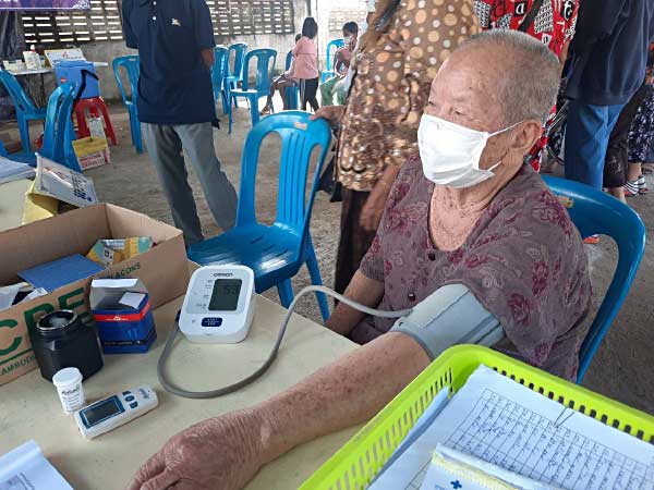 An elderly community member receives a blood pressure test during a visit for COVID-19 vaccination