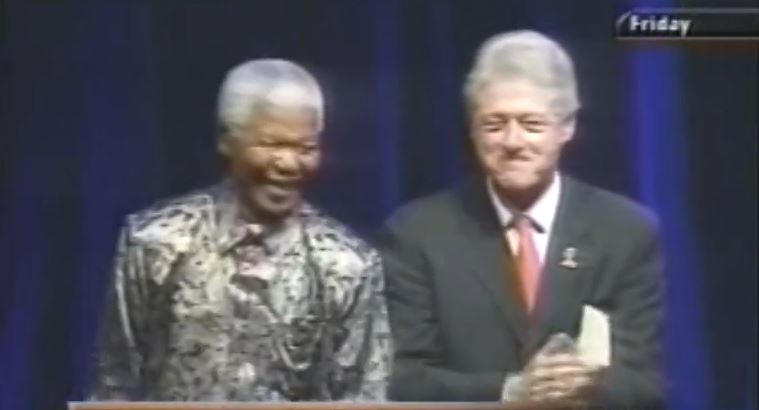 Former South African and US presidents Nelson Mandela and Bill Clinton stand on stage after speaking at IAS 2002. 