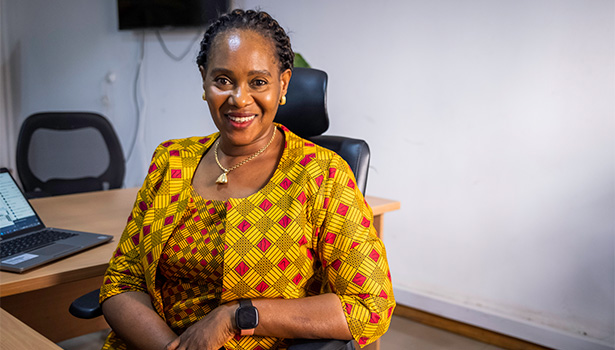 Photo of a smiling Nigerian woman sitting at a desk.