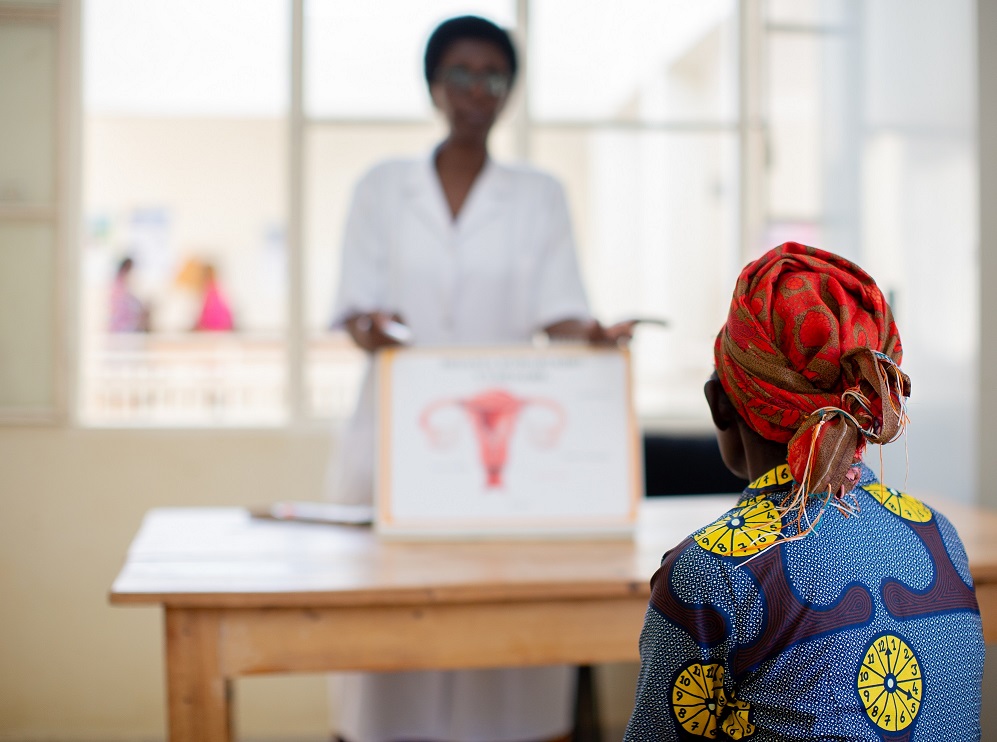 Nurse uses a poster to explain cervical cancer to a patient in Rwanda