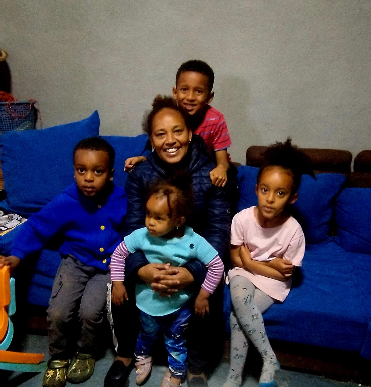 A woman with her four children sitting on a blue couch